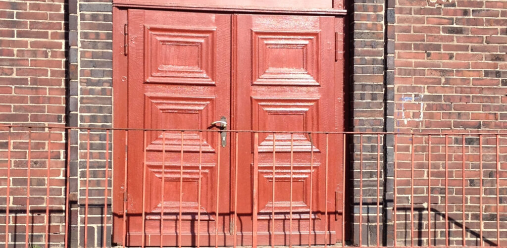 Rot lackierte Tür eines Backsteingebäudes